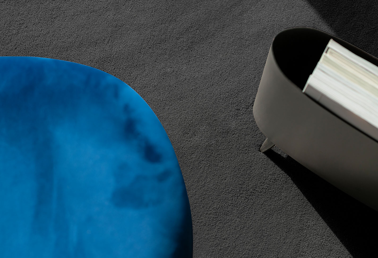 Antraciet vloerkleed op maat met blauwe stoel